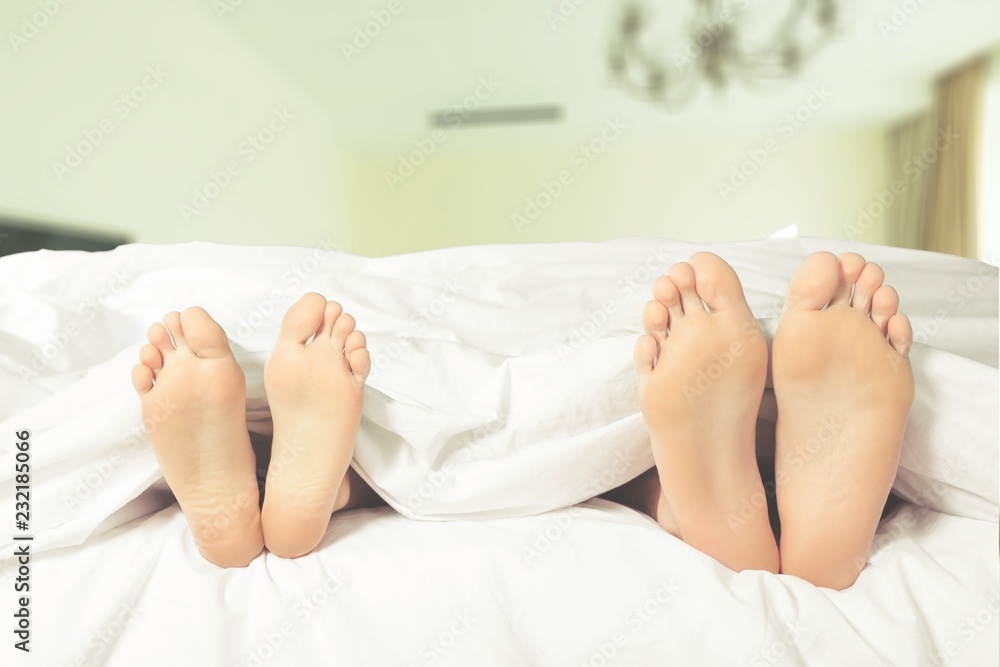 Beautiful feet of a young couple lying in bed close up Beautiful feet of a young couple lying in bed close up