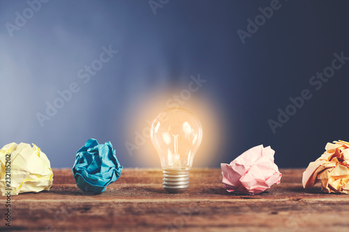 lightbulb with crumpled paper on wooden desk photo