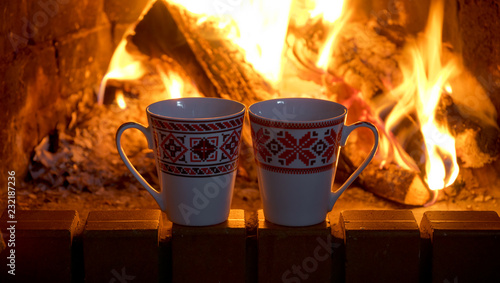 Two tea cups on the background of a burning fireplace