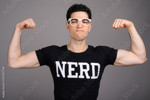 Young handsome nerd man with eyeglasses against gray background © Ranta Images