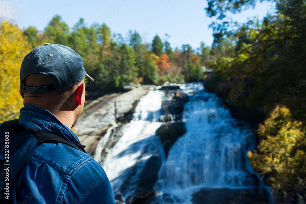 Hiker enjoying the beauty of High Falls in Dupont State Forest in the fall. Hiker enjoying the beauty of High Falls in Dupont State Forest in the fall.