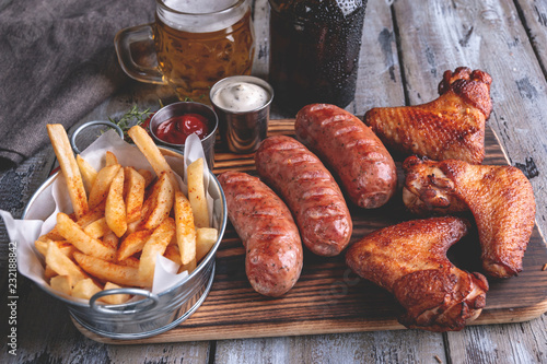 Fried chicken wings,grilled sausages, french fries, white and red sauce. food to beer