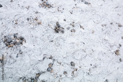 Frostiger Boden mit Fußabdrücken und Kieselsteinen