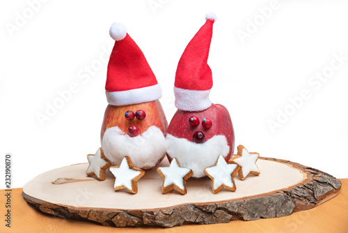 zwei lustige selbstgebastelte Nikolausäpfel auf einem Holzbrett mit Zimtsternen photo