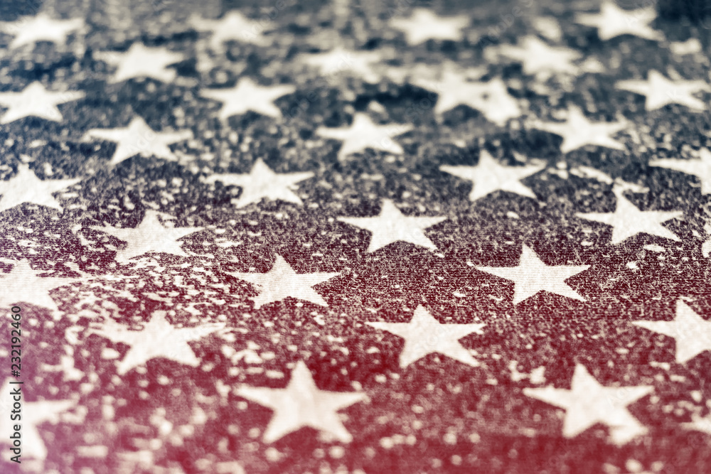 Fototapeta premium Close-up of a grungy print of stars from the american flag with horizontal red light leak. Concept of political division in the United States.