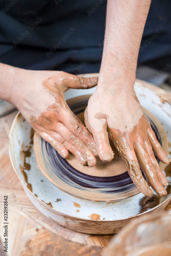 Professions Ideas. Closeup of Male Hands Working with Lump of Clay on Potter's Wheel in Workshop. Pressing it for Getting Form and Shape.