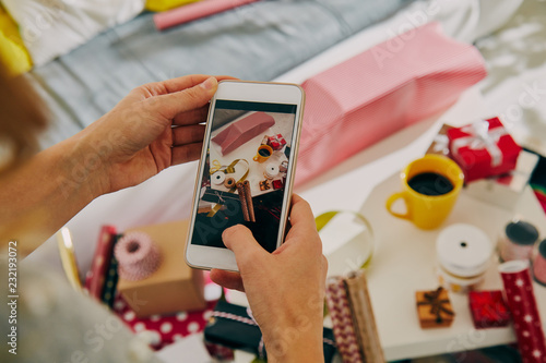 Woman using cellphone while preparing presents for family and friends  for Christmas and New Year. Holiday concept.