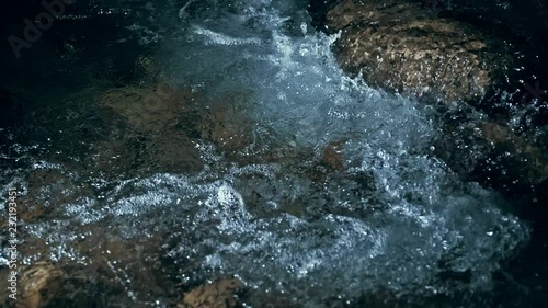 Slow motion of waves on dark water surface with play of flecks of bright light close up. Amazing dramatic natural background. Shooting with 180fps. Epic mystical and magic night view. Crystal clear
