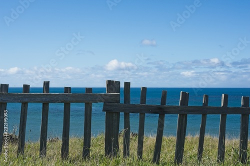 Wooden Fence serving as  barrier at the edge of a grassy overllo at the Pacific Ocean in Mendocino County  California