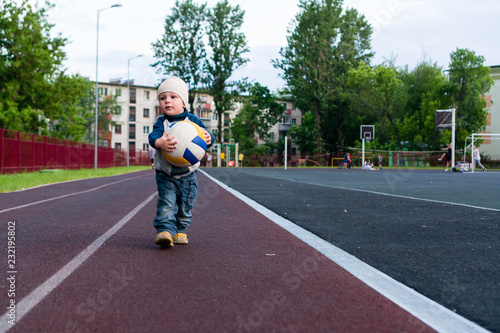 child boy playing with a ball at a sports stadium