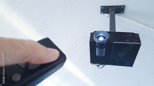 Fotografie hand turning on the projector from the remote control in the meeting room