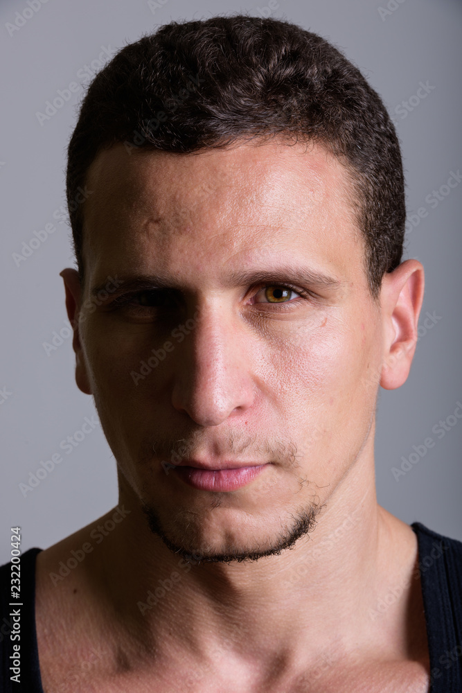 Face of young muscular Persian man against gray background Face of young muscular Persian man against gray background