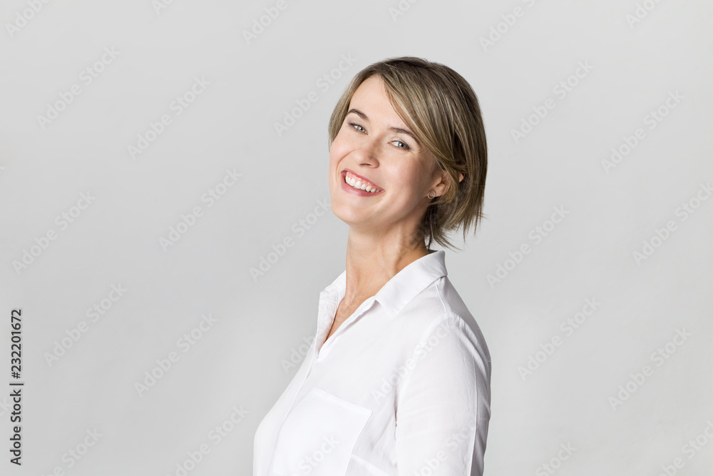 Smiling positive female with attractive look, wearing white elegant shirt posing against white wall Smiling positive female with attractive look, wearing white elegant shirt posing against white wall