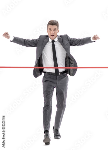 Happy businessman running through finishing line.