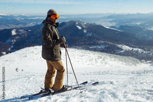 Nice man skiing in the mountains. Good skiing in the snowy mountains,  Winter is coming, first snowfall. Ski resort season is open. Ski equipment, trail. 