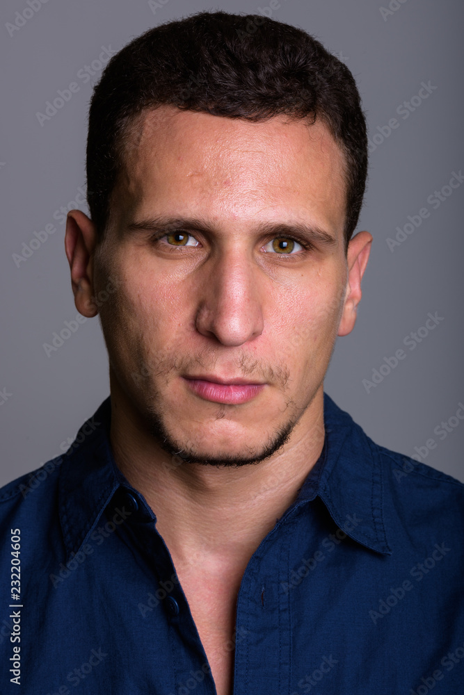 Face of young muscular Persian man against gray background Face of young muscular Persian man against gray background