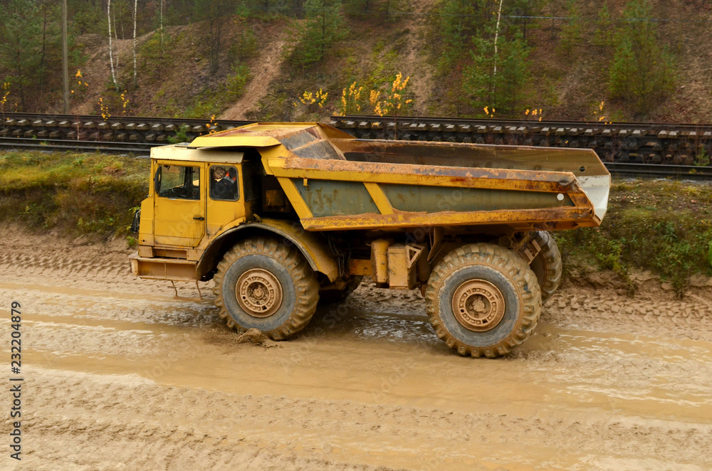 Earth mover loading dumper truck with sand in quarry. Excavator loading sand into dumper truck.Quarry for the extraction of minerals. Large quarry dump truck. Production useful minerals. Earth mover loading dumper truck with sand in quarry. Excavator loading sand into dumper truck.Quarry for the extraction of minerals. Large quarry dump truck. Production useful minerals.
