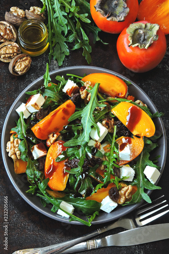 Healthy salad with persimmon, arugula, nuts and feta cheese. Fitness food. Superfoods Vitamin autumn persimmon salad.