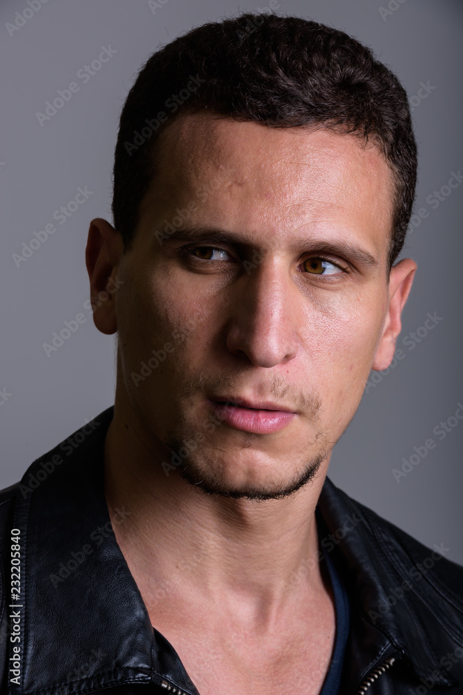 Face of young muscular Persian man thinking while looking suspic Face of young muscular Persian man thinking while looking suspic