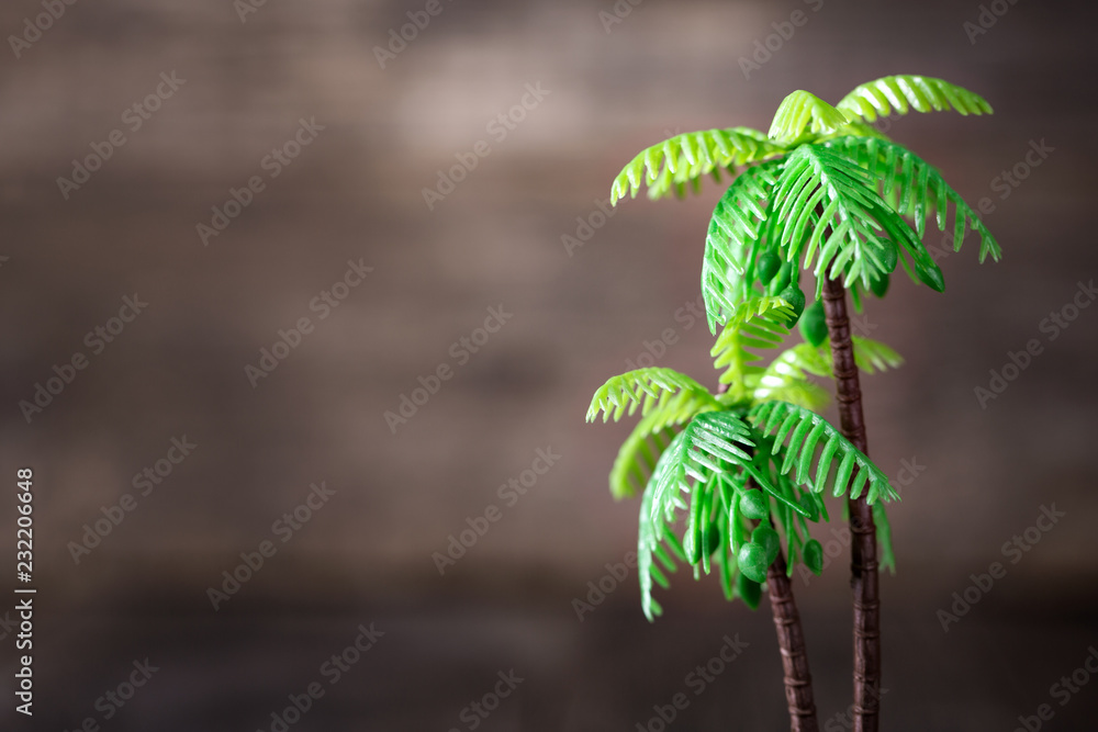 Fototapeta premium Small toy of palm tree on wooden background