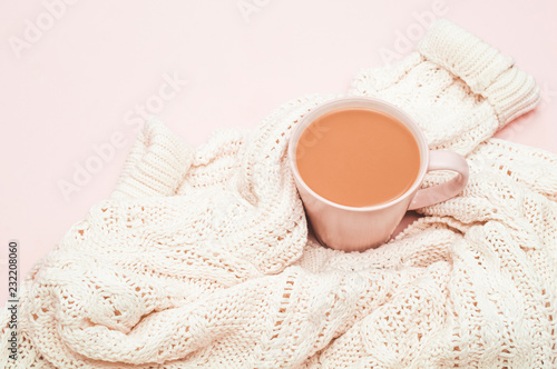 Cup of coffee with milk and a sweater on a pink background