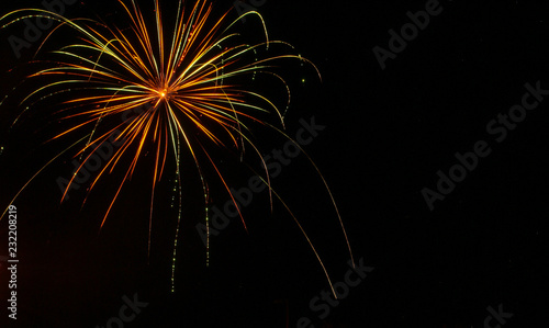 Green  gold  and red trailing light of firework against a black sky on the fourth of July