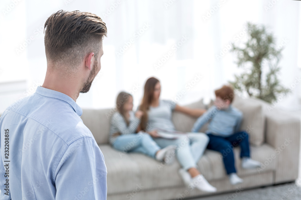 man standing in his living room and looking at his family man standing in his living room and looking at his family