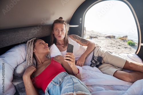 Wake up. Young couple of good-looking travelers waking up in their compact trailer in the morning