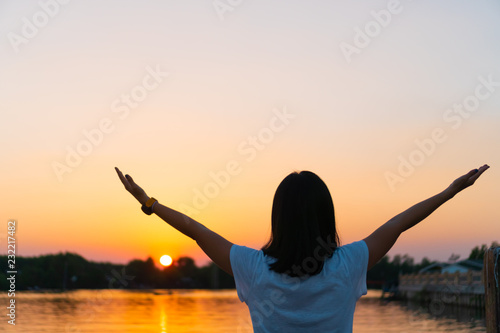 Woman rise hands to sky feel relax breeze and fredo to beautiful sunset sky and river background.