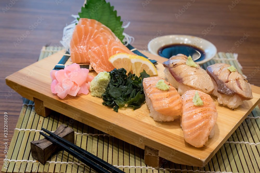 Mixed salmon sushi on wooden plate along with Japanese sauce and green leaf decoration, Japanese food, close up at sushi .. Mixed salmon sushi on wooden plate along with Japanese sauce and green leaf decoration, Japanese food, close up at sushi ..
