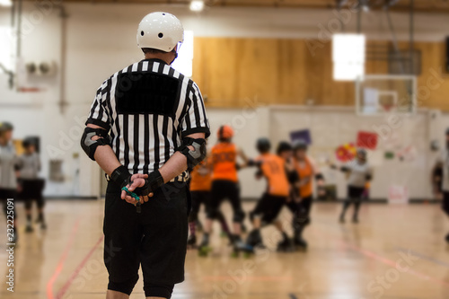 Roller derby referee watches teams for penalties