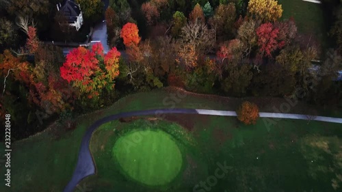 Flying above the stunning colorful treetops and golf course in Louisville with leaves turning colors on sunny morning. Beautiful autumn trees in yellow, orange and red forest on sunny autumn day. Fall