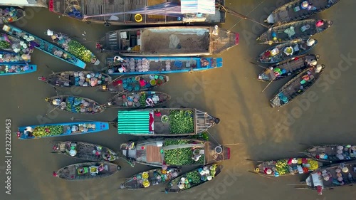 AERIAL, TOP DOWN: Flying away from people selling produce from wooden boats floating around the tranquil murky delta in the Vietnamese countryside. Scenic shot from above of a bustling floating market