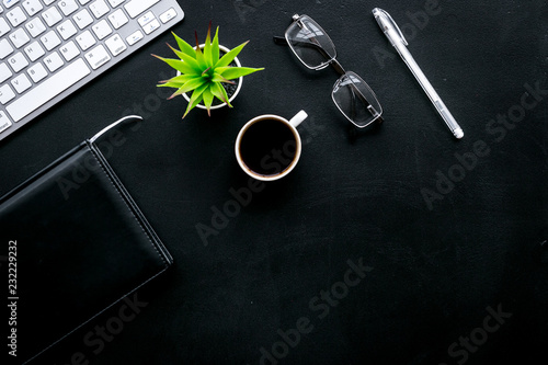 Office desk of chief, director or top manager. Computer keyboard, expensive black notebook, glasses, coffee on black background top view space for text