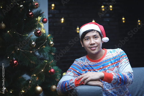 Asian Man With Christmas Costume Sitting Beside Christmas Tree