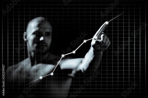 Young man in growth concept with a graph.Serious man drawing strategy on virtual screen on dlack isolated background photo