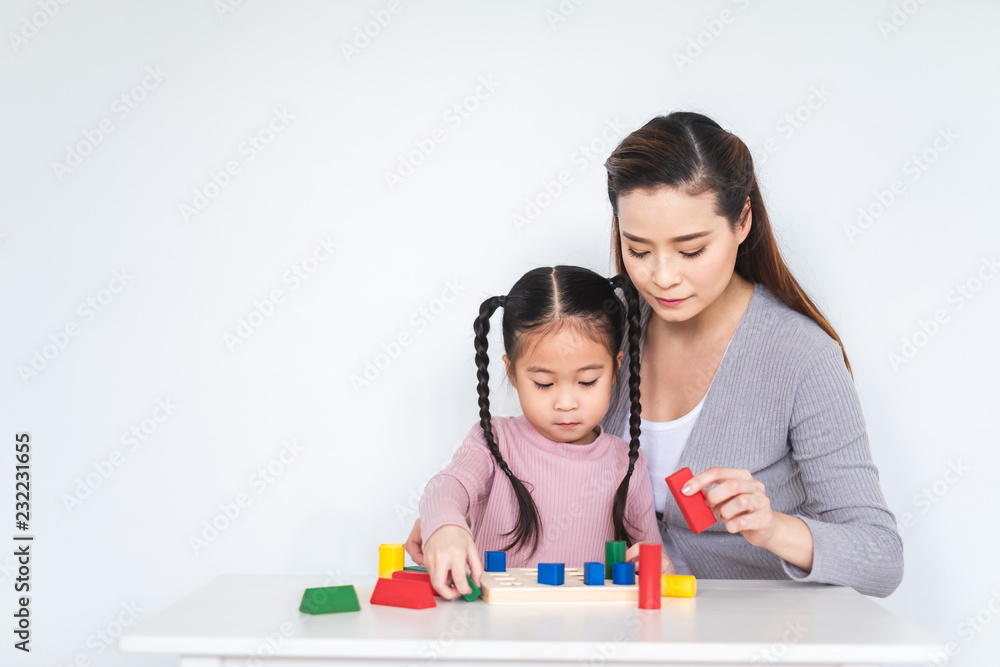 Asian girl daughter playing blocks toy with mother over white background, happy family concept Asian girl daughter playing blocks toy with mother over white background, happy family concept