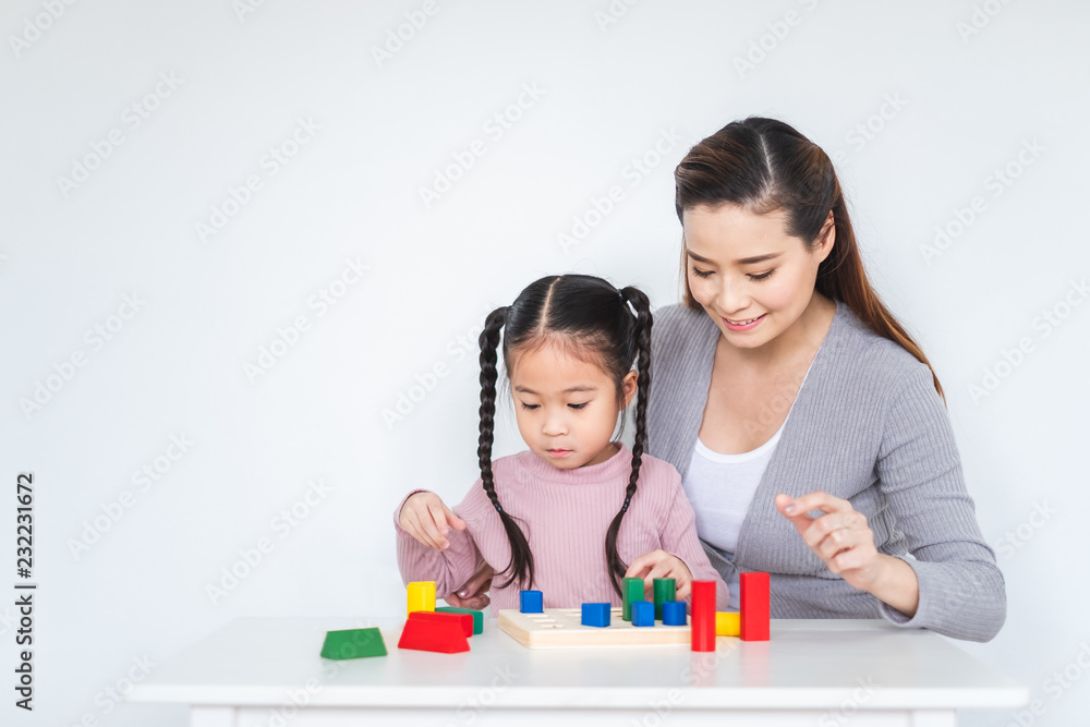 Asian girl daughter playing blocks toy with mother over white background, happy family concept Asian girl daughter playing blocks toy with mother over white background, happy family concept