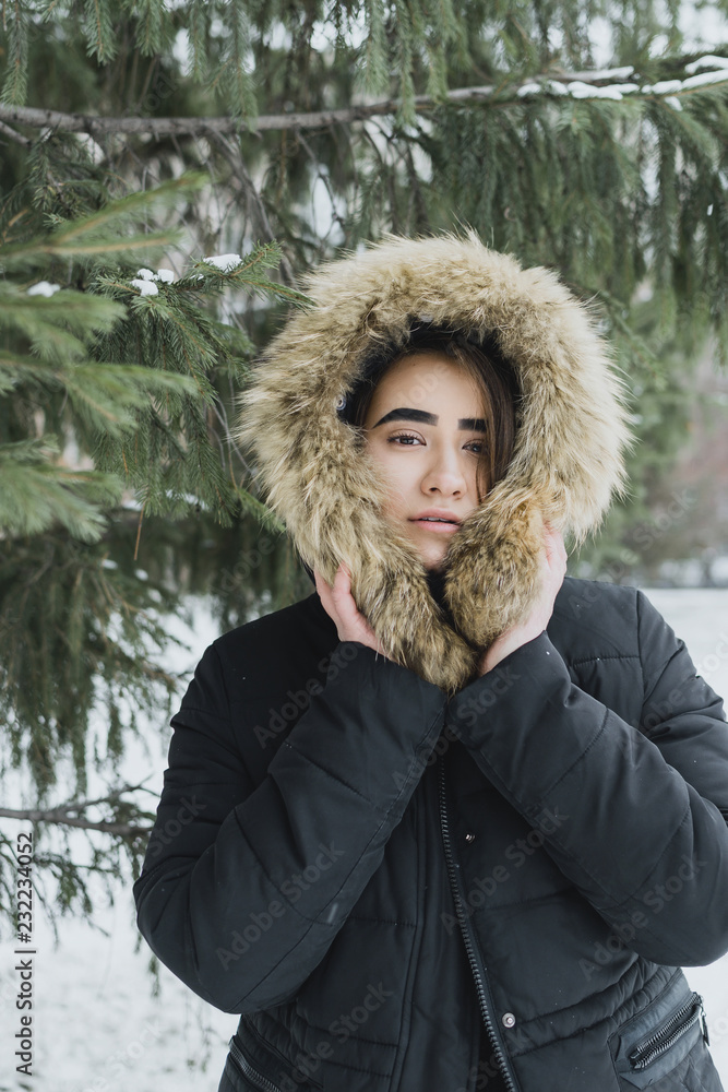 Lifestyle portrait of young adult female in warm winter clothing hiding in the hood, selective focus Lifestyle portrait of young adult female in warm winter clothing hiding in the hood, selective focus