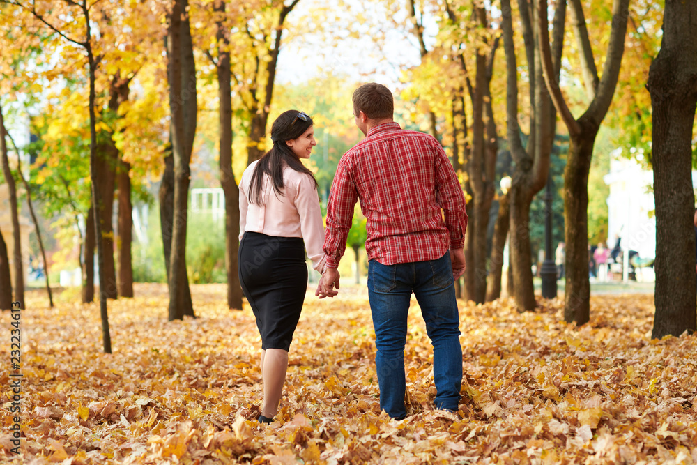 Couple is walking in autumn city park. Bright yellow trees. Couple is walking in autumn city park. Bright yellow trees.
