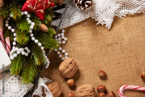 Christmas decoration background, fir tree, textile, beads, gifts, old paper, nuts and other stuff on sackcloth. Empty space for text, new year theme.