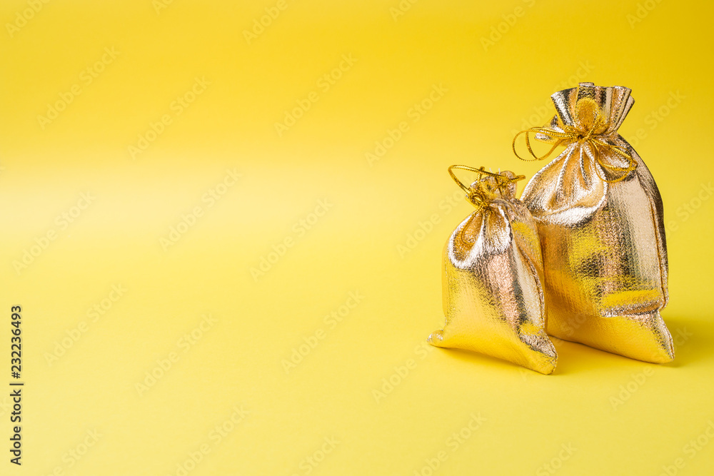 Christmas new year concept. Golden gift bag on a yellow background. Copy space - obrazy, fototapety, plakaty 