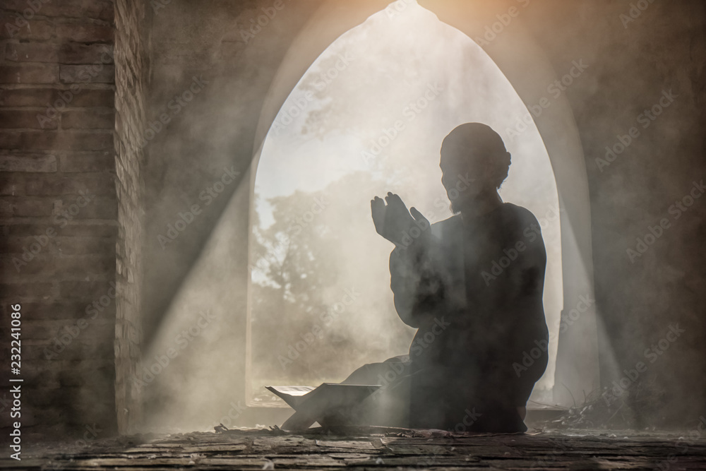 Silhouette of muslim male praying in old mosque with lighting and smoke background - obrazy, fototapety, plakaty 