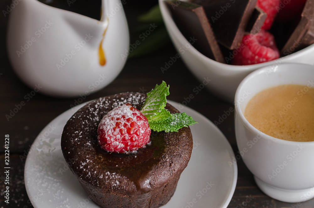 Chocolate fondant with raspberryand coffee cup. Molten chocolate cake with powdered sugar background. Chocolate fondant with raspberryand coffee cup. Molten chocolate cake with powdered sugar background.