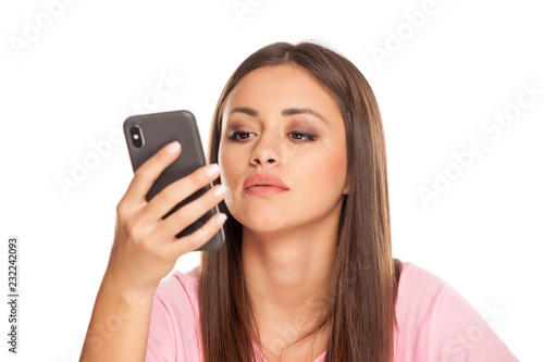 pensive young woman look in her smartphone on white background