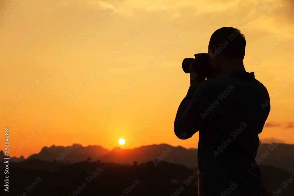 Photographer silhouette shooting landscape at sunset background.