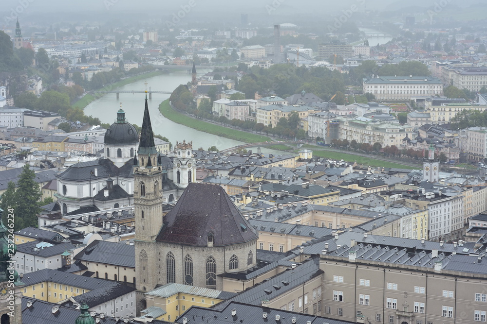 View of city of Salzburg on banks of river Salzach from Salzburg Fortress on overcast day.