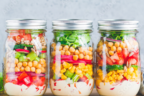 Glass jars with layering various vegan salads for healthy lunch. The concept of fitness and vegetarian food.