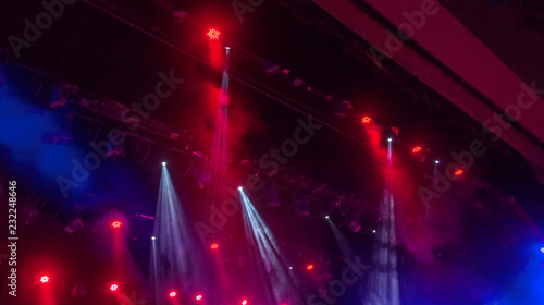 Stage lights. Several projectors in the dark. Multi-colored light beams from the stage spotlights on the stage in the smoke at the time of the entertainment show. Night club. Lights show. Lazer show