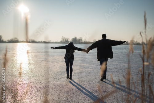 Couple carefully stepping together on frozen lake